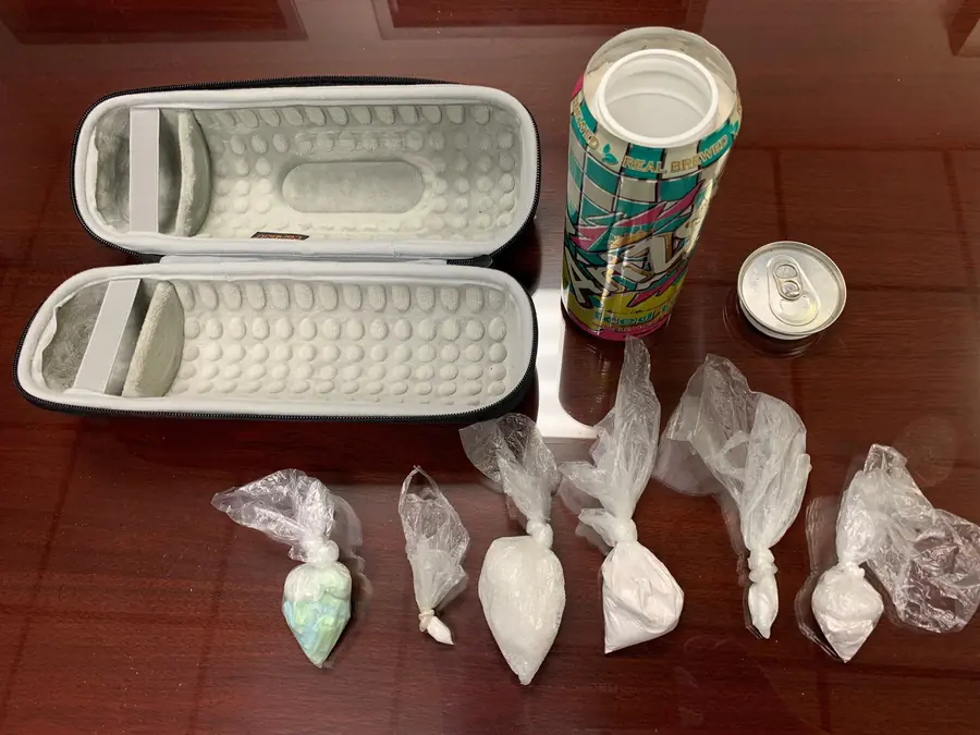 Seized fentanyl and methamphetamine in small plastic bags next to a hollowed-out drink can and a hard case
